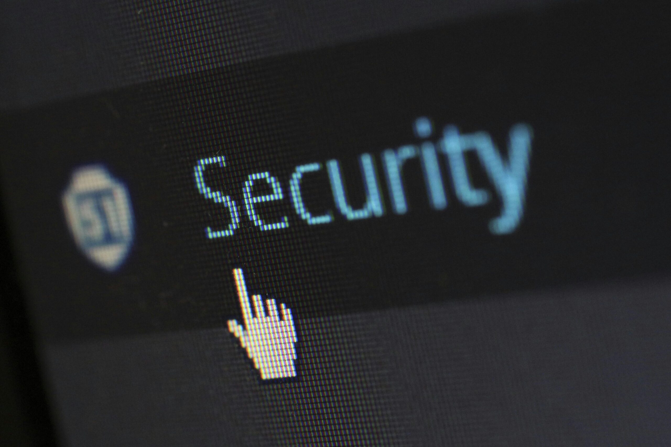 Close-up van een computerscherm met het woord “Security” naast een schildpictogram. Een handvormige cursor wijst naar de tekst.