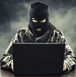 Op de foto iemand achter een computer met een bivakmuts.