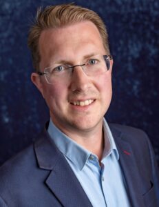 Op de foto staat Johan Kroes kijkend in de camera. 
