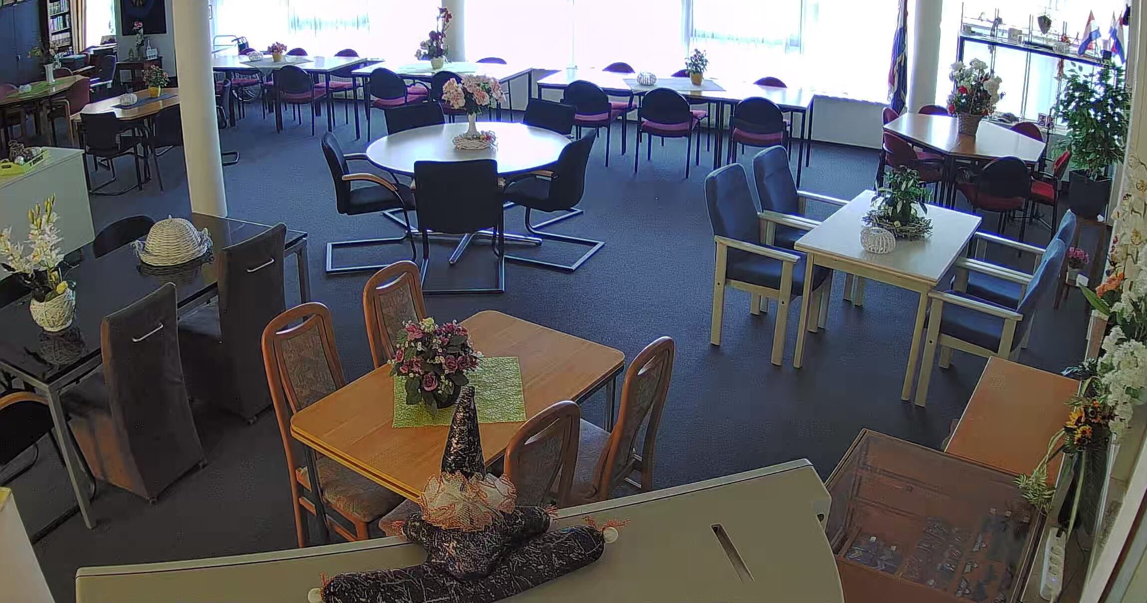 kantine met meerdere tafels en stoelen en een grote raampartij.