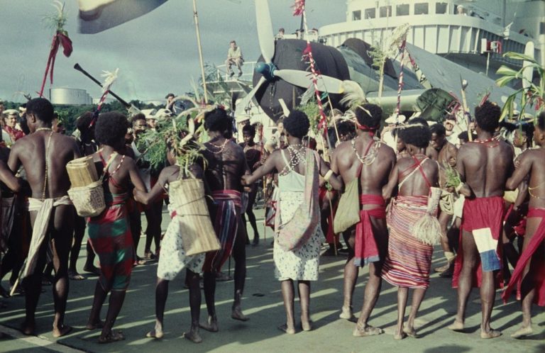 Op het vliegdek van het vlaggeschip Hr. Ms. Karel Doorman (1948-1968) laten Papoea's (Biakkers - Noemforesen en Arfakkers) hun traditionele dansen zien.